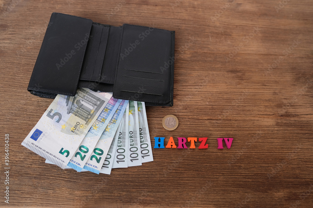 money, euro banknotes, black wallet, word in German Hartz IV made of colored letters lie on old wooden table, concept of social assistance to poor, unemployment benefit money, euro banknotes, black wallet, word in German Hartz IV made of colored letters lie on old wooden table, concept of social assistance to poor, unemployment benefit
