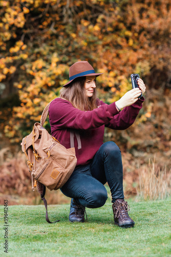 woman in hat taking photos with a phone in the park © Iryna