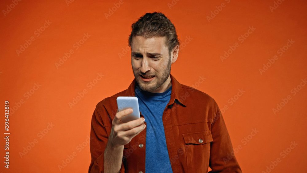 sad young man using mobile phone on orange sad young man using mobile phone on orange