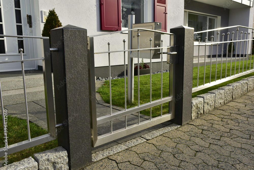 Moderner Edelstahlzaun mit polierten Natursteinpfosten um den