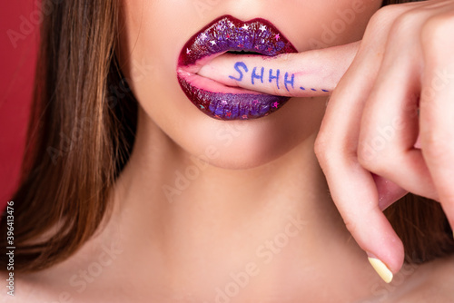 Shhh woman. Shh, Womens secrets. Female with finger in mouth. Closeup of young woman is showing a sign of silence with shhh written on the finger.
