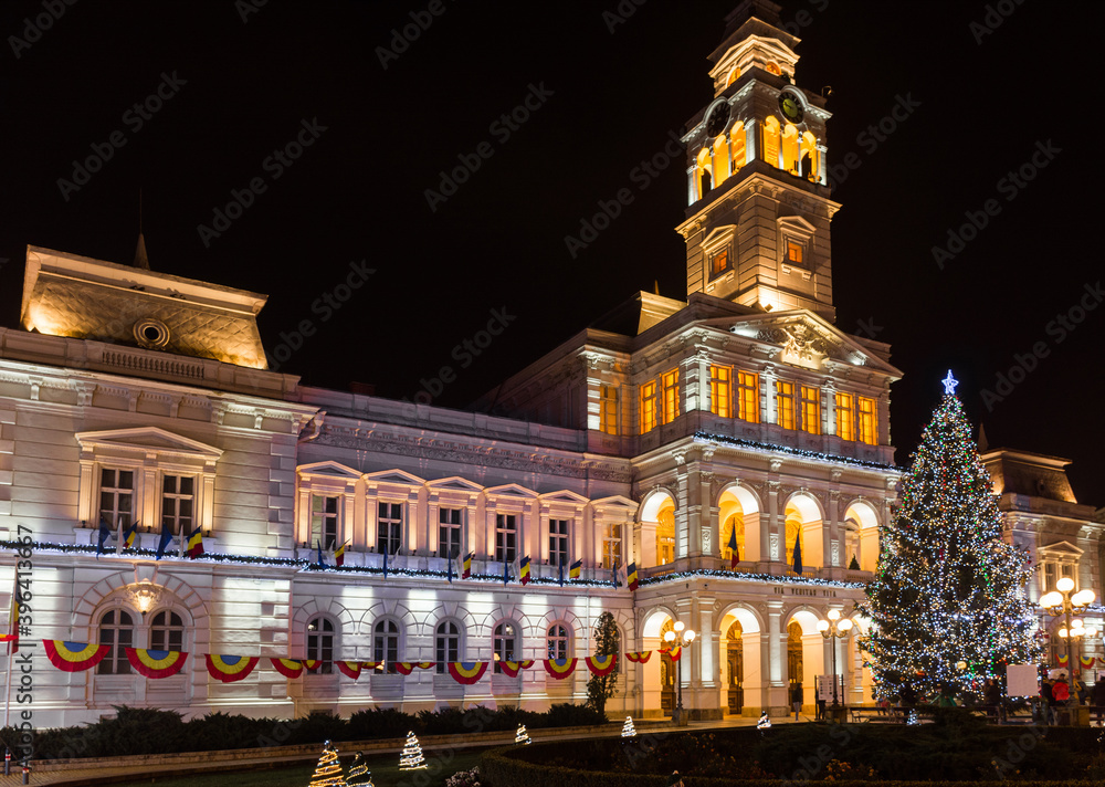 Christmas tree and new year decorations in front of the town hall building, at night, in the city center of Arad, Romania
