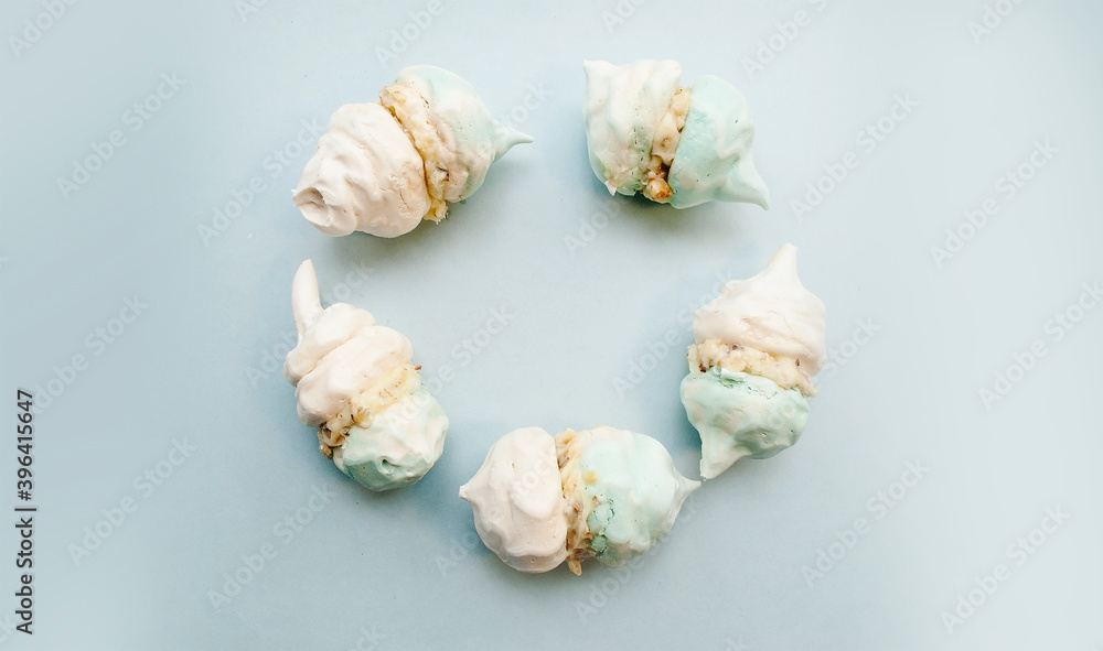 White-blue meringue with cream laid out in a circle. Blue background, place for text. Copy space. White-blue meringue with cream laid out in a circle. Blue background, place for text. Copy space.
