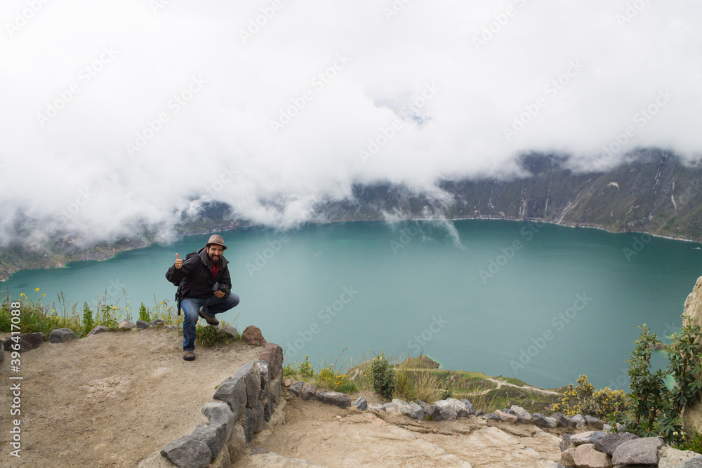 traveler man photographer hat in spectacular landscape crater lake with fog quilotoa volcano ecuador latin america