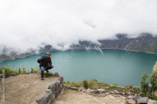 traveler man photographer hat in spectacular landscape crater lake with fog quilotoa volcano ecuador latin america © Marcela