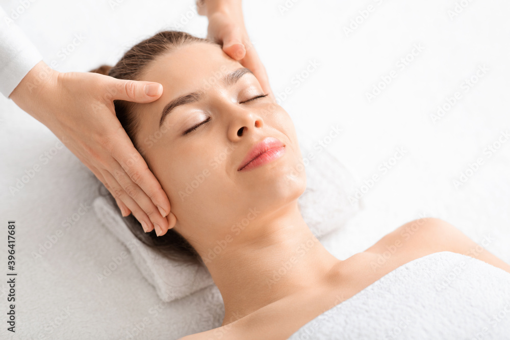 Joyful young woman relaxing during face lifting massage, copy space Joyful young woman relaxing during face lifting massage, copy space