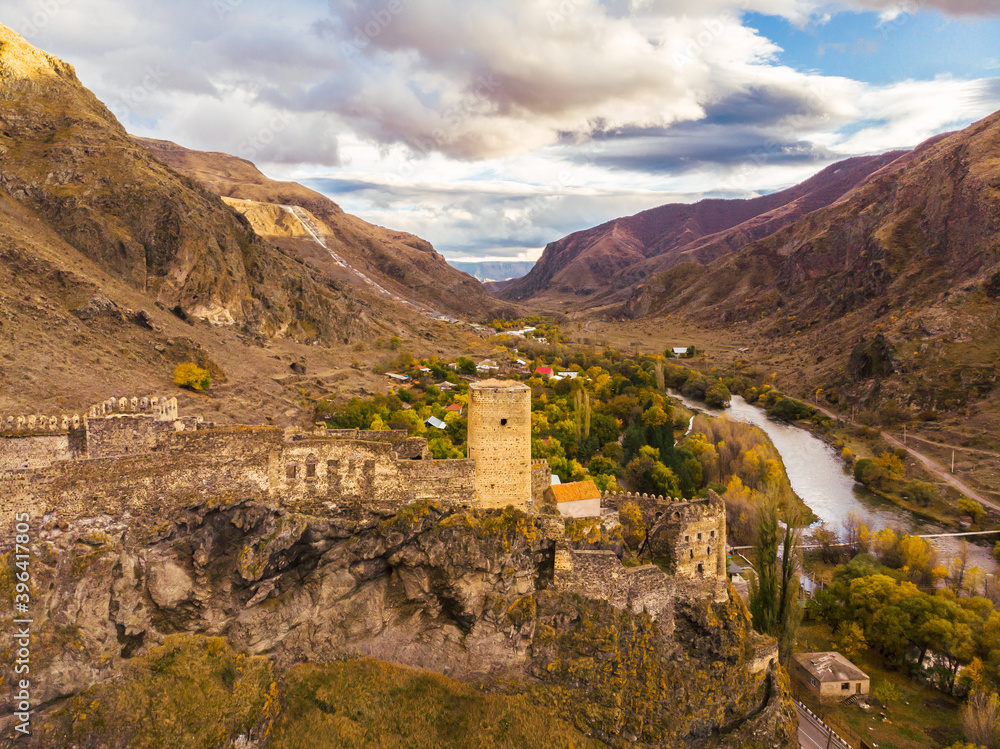 Khetvisi fortress from aerial perspective surounded by colorful autumn nature with paravani river on the right and dramatic sky in the background. Historical sights in Georgia.