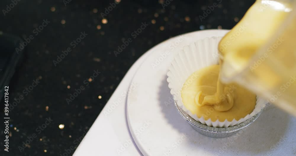Close up slow motion pouring cake dough into white paper forms on baking tray , preparing cooking homemade muffins banana cupcake Close up slow motion pouring cake dough into white paper forms on baking tray , preparing cooking homemade muffins banana cupcake
