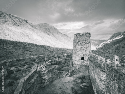 Sepia background image of historical site in Georgia. Khertvisi fortress tower and alls with mountains background. photo