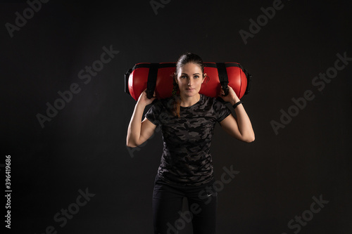 Fitness woman with Aqua Bag, stands on the shoulders of a bag. Sports on a black background Smiling looks at the camera