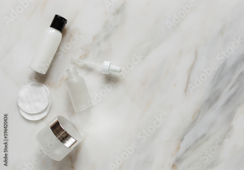 flat lay of beauty products on marble surface with empty space on the right, cream, bottle, dropper bottle, nail polish, white, pink, mock up for a banner, beauty blog 