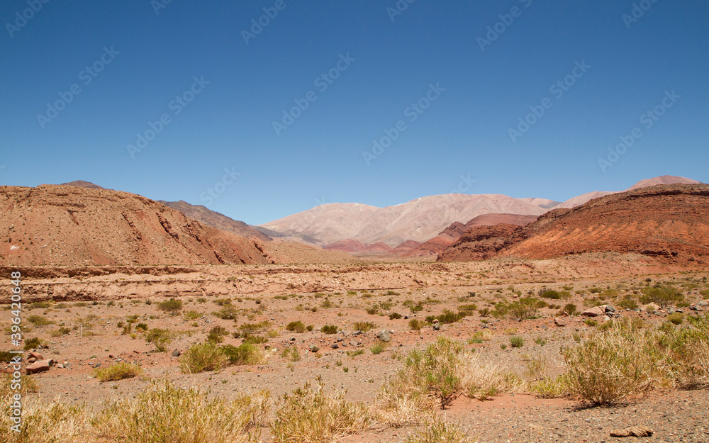 Desert landscape. View of the arid valley, red sand, sandstone formations and mountains under a deep blue sky. Desert landscape. View of the arid valley, red sand, sandstone formations and mountains under a deep blue sky.