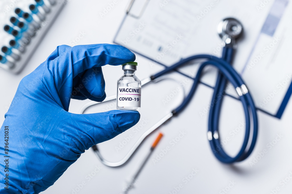 Doctor, scientist or nurse's hand in blue gloves holding vial coronavirus vaccine shot for diseases outbreak vaccination, medicine and drug concept Doctor, scientist or nurse's hand in blue gloves holding vial coronavirus vaccine shot for diseases outbreak vaccination, medicine and drug concept