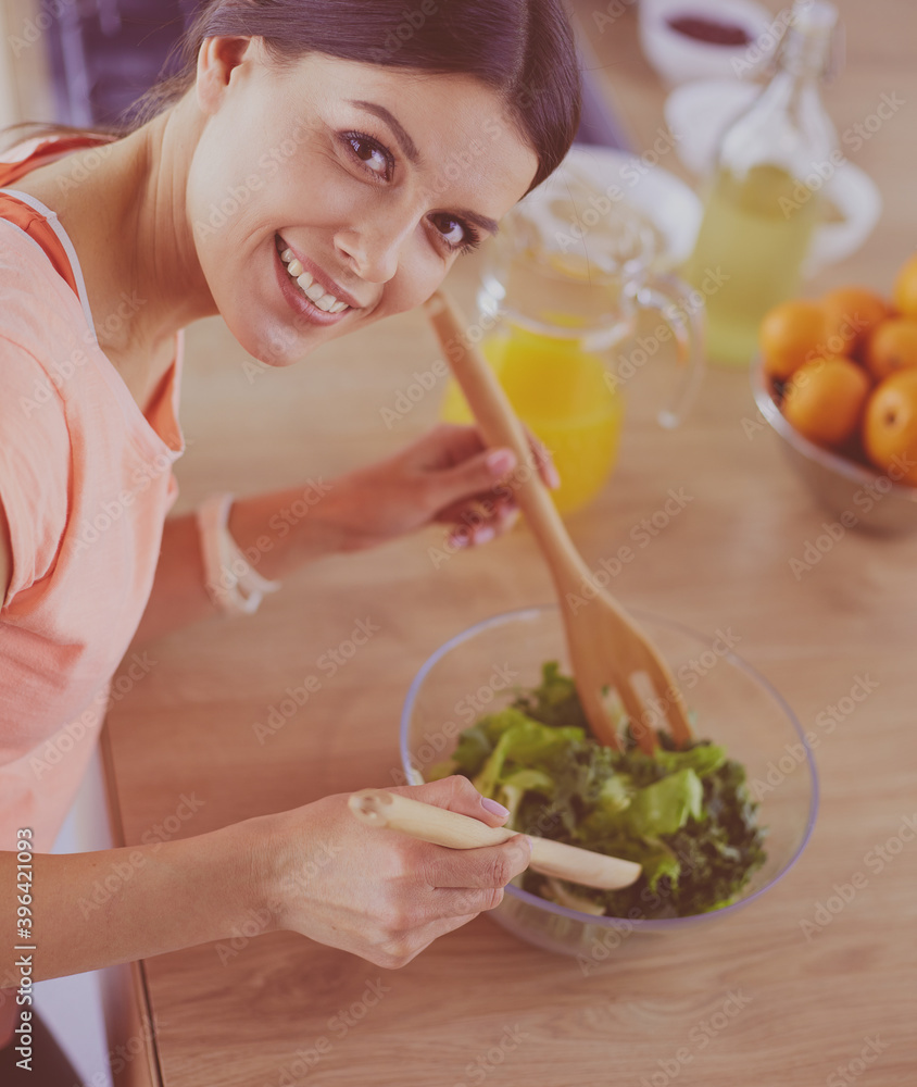 Smiling young woman mixing fresh salad in the kitchen. Smiling young woman mixing fresh salad in the kitchen.