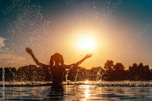 happy female in red bikini splashing or play in water and have fun at sunset