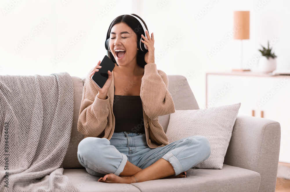 Happy asian lady singing using smartphone as mic Happy asian lady singing using smartphone as mic