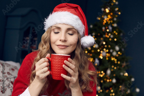 gorgeous blonde woman in red sweater and Santa hat with cup of coffee