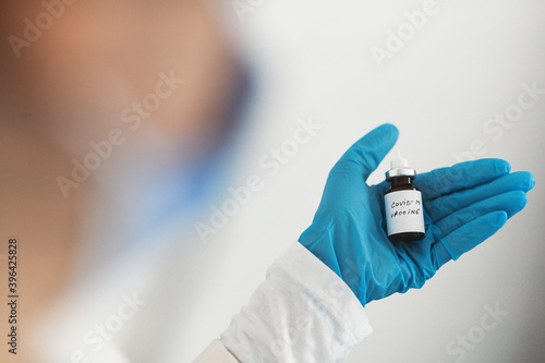 Female doctor holding in her hand coronavirus vaccine - covid-19 health concept
