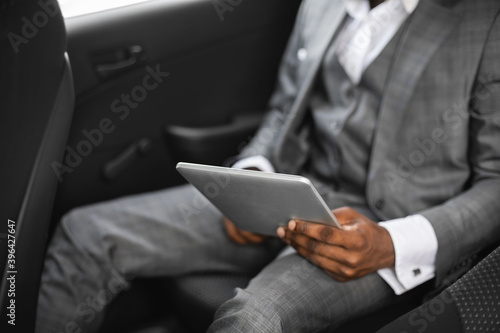 Cropped of african businessman going by car, using pad