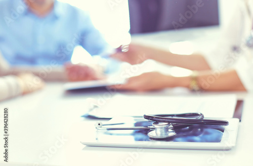 Close up of doctor and patient sitting at the desk near the window in hospital