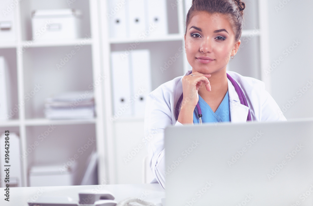 Female doctor sitting on the desk and working a laptop in hospital Female doctor sitting on the desk and working a laptop in hospital