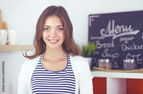 Young woman standing near desk in the kitchen