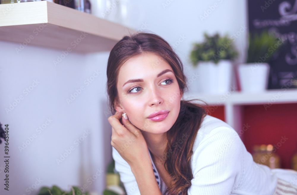 Young woman standing near desk in the kitchen. Young woman . Young woman standing near desk in the kitchen. Young woman .