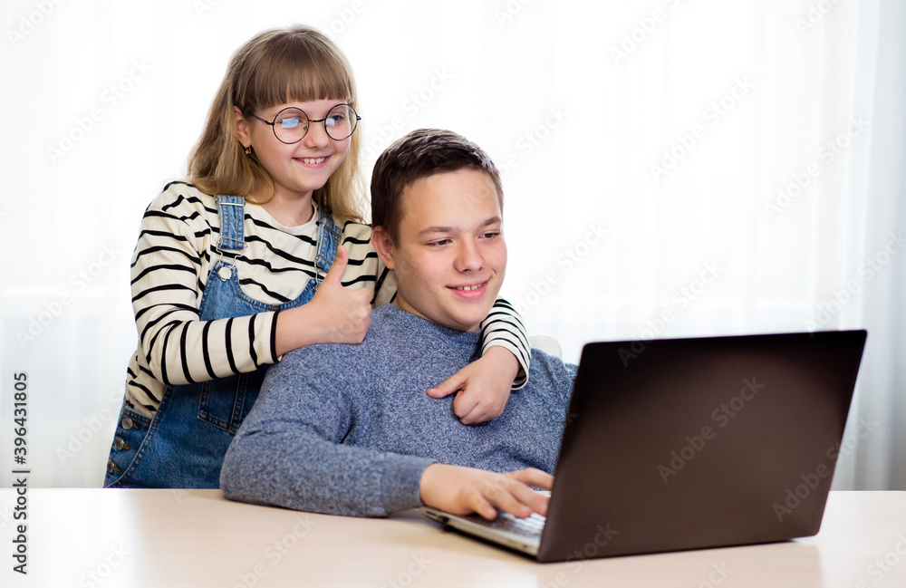 Smiling children communicate with friends online on a laptop Smiling children communicate with friends online on a laptop