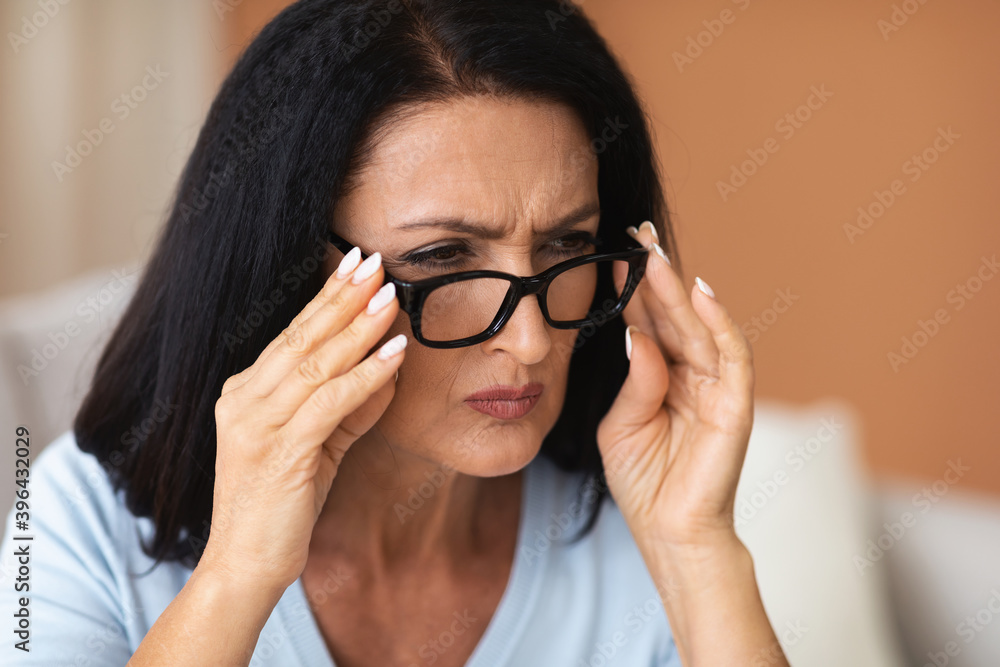 Mature Woman Squinting, Trying To Look Closer Through Eyeglasses Mature Woman Squinting, Trying To Look Closer Through Eyeglasses