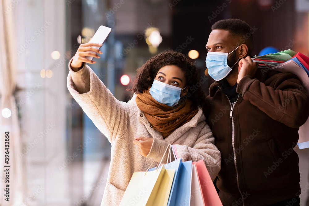 Black couple in masks taking selfie after shopping - obrazy, fototapety, plakaty 