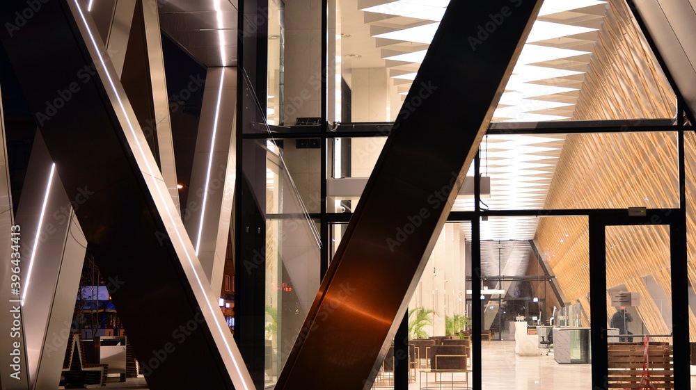 Obraz premium Combination of metal and glass wall material. Steel facade on columns. Abstract modern architecture. High-tech minimalist office building. Contemporary business architecture abstract fragment in night