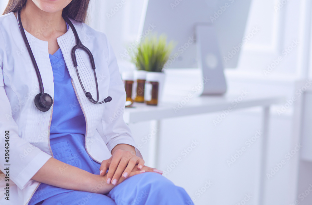 Beautiful female doctor sitting in a consulting room, smiling at the camera Beautiful female doctor sitting in a consulting room, smiling at the camera