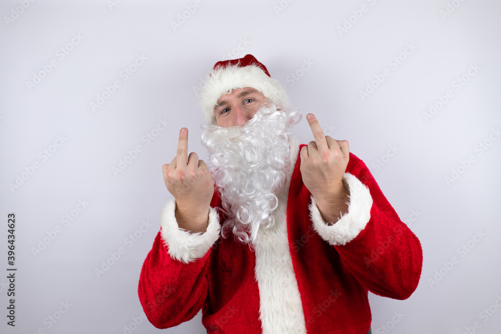 Man dressed as Santa Claus standing over isolated white background showing middle finger doing fuck you bad expression, provocation and rude attitude. screaming excited Man dressed as Santa Claus standing over isolated white background showing middle finger doing fuck you bad expression, provocation and rude attitude. screaming excited