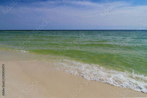 Fototapeta Naklejka Na Ścianę i Meble -  Close-up green wave on the ocean shore, small wave creates foam, shooting from the beach