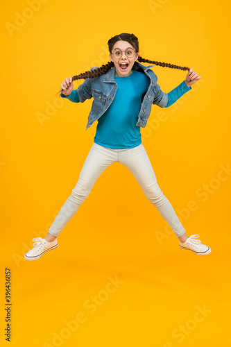 happy jumping child girl in glasses for eyesight has fashionable hairstyle having fun, energy