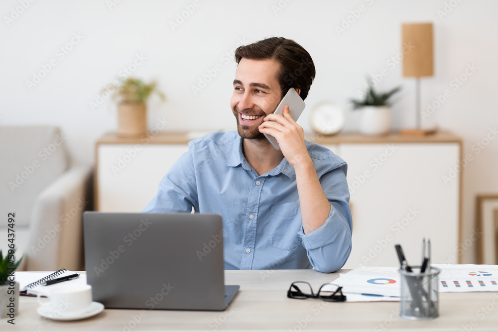 Cheerful Businessman Talking On Phone In Office Sitting At Workplace