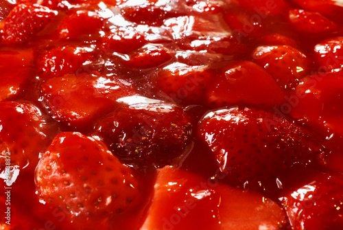 Strawberry jelly with fruits from a top of cake, vivid red strawberry background