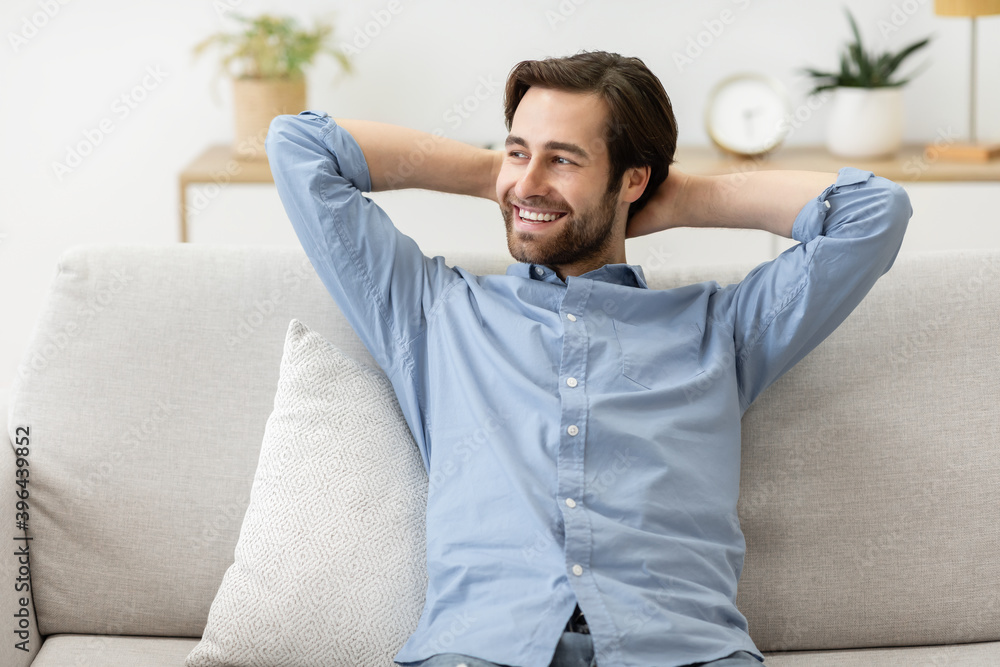 Obraz premium Happy Relaxed Man Sitting On Sofa At Home On Weekend