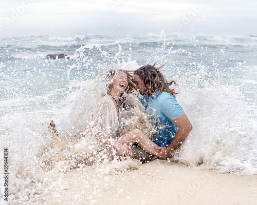 Beautiful young couple in a wave splash