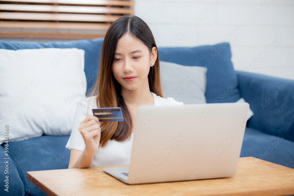 Young asian woman sit on sofa using laptop computer shopping online with credit card buying to internet, happy girl payment with e-business on couch, purchase and payment, business concept. Young asian woman sit on sofa using laptop computer shopping online with credit card buying to internet, happy girl payment with e-business on couch, purchase and payment, business concept.