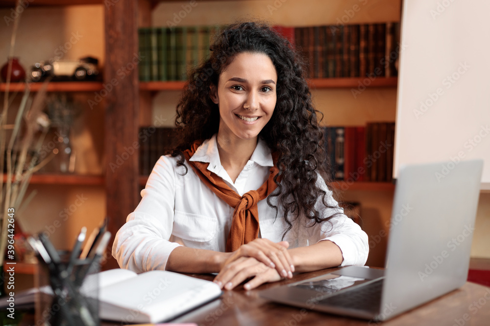 Confident woman posing sitting at desk with laptop Confident woman posing sitting at desk with laptop