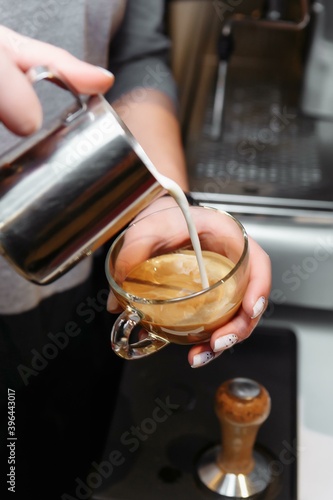 Closeup of barista pouring milk into art cappuccino or latte