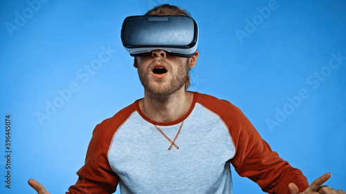 shocked young man in virtual reality headset on blue