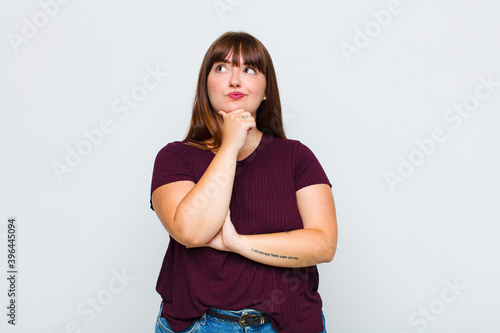overweight woman thinking, feeling doubtful and confused, with different options, wondering which decision to make photo