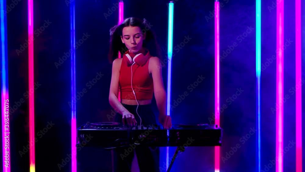 Portrait of a young pretty woman in big red headphones plays turntables electronic dance music and dances. Slow motion. Portrait of a young pretty woman in big red headphones plays turntables electronic dance music and dances. Slow motion.