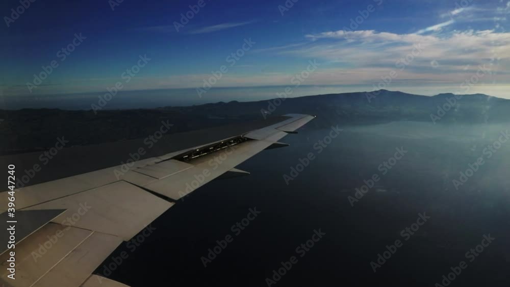 Airplane wing with São Migel's island in the Azores on the background in the morning Airplane wing with São Migel's island in the Azores on the background in the morning