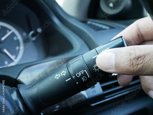 hand adjusting car headlight control switch in a modern car.
