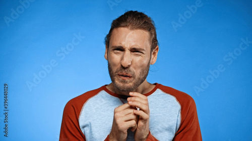 disgusted young man looking at camera on blue