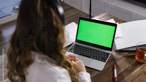 Young business woman with her laptop - green screen display - home shooting