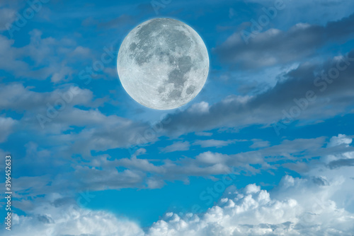 Full moon on the blue sky with clouds.